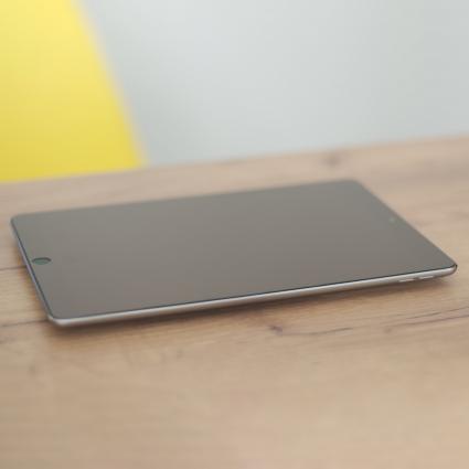 Tablet z założonym szkłem hartowanym Wozinsky Tempered Glass leżący na stole